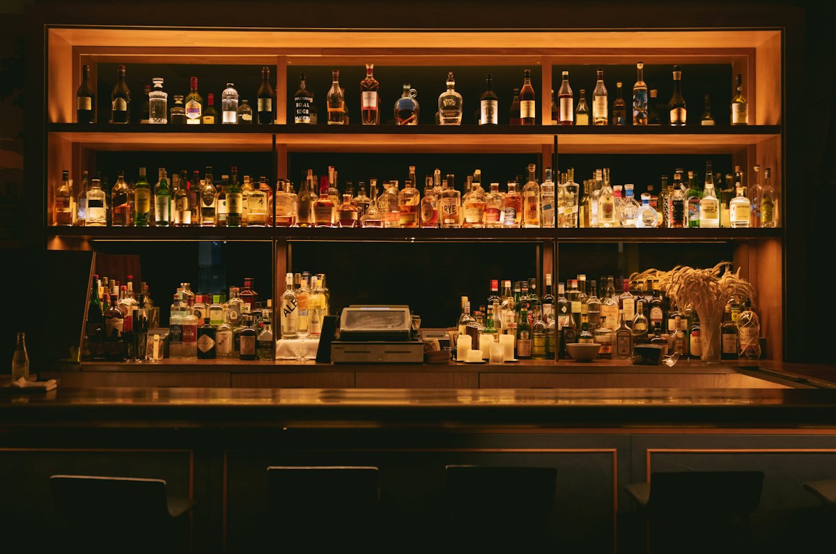 Bottles on wooden shelves behind a bar
