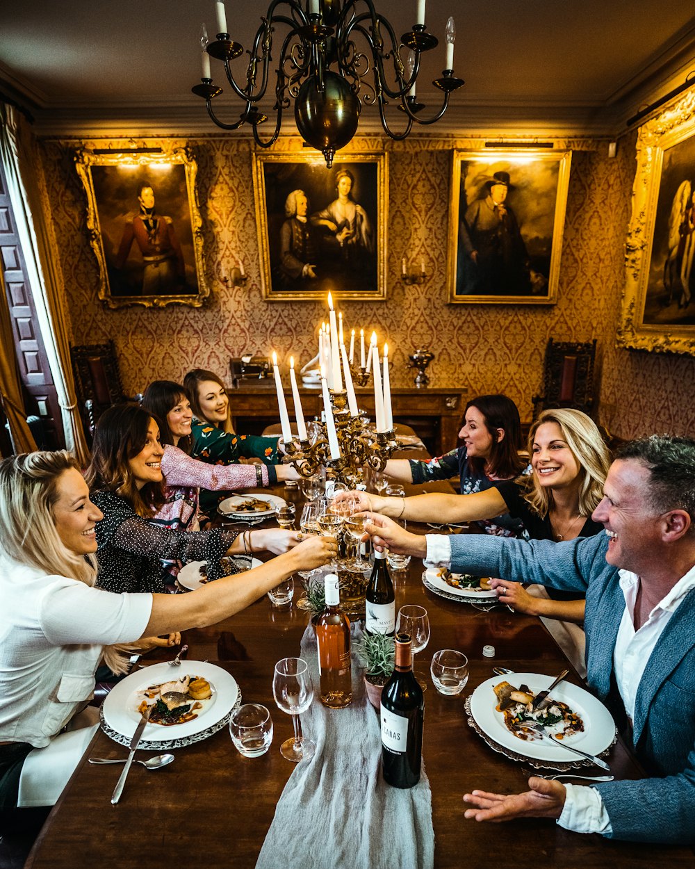 A group of friends at a candlelit table, raising their glasses