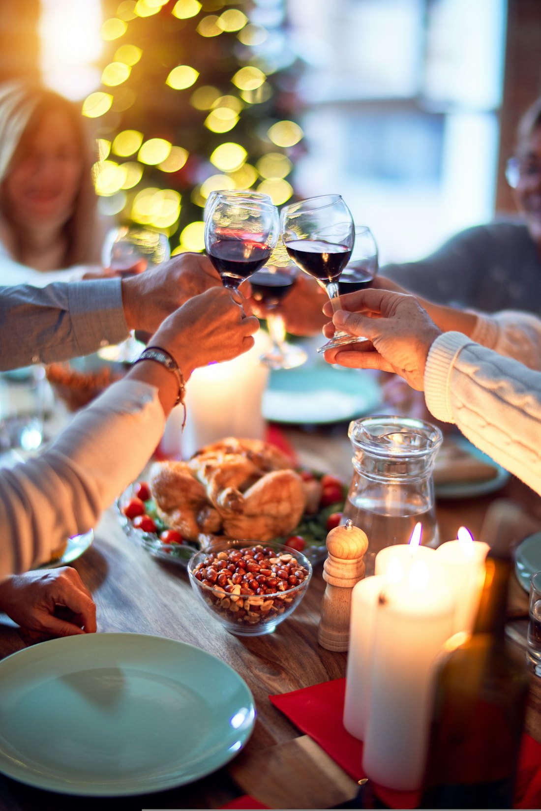 Friends clinking glasses of red wine over a table full of food