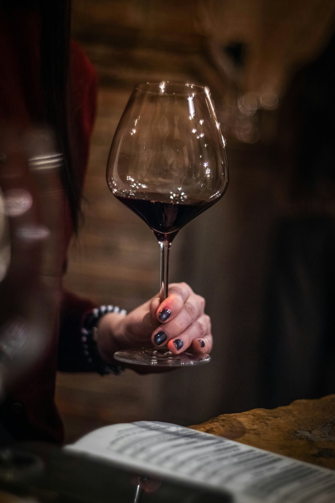A hand holding up a glass of red wine
